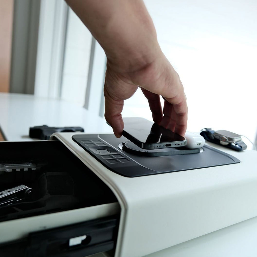 Person placing a phone on the Vaultek DS5i Smart Station ViSN Biometric for wireless charging.