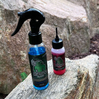 Riptide Armory Advanced Gun Cleaner & Advanced Oil 2 Step Kit bottles on a rock outdoors
